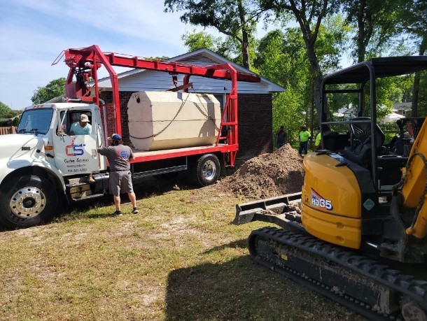 Custom Services truck delivering a septic tank alongside our excavator
